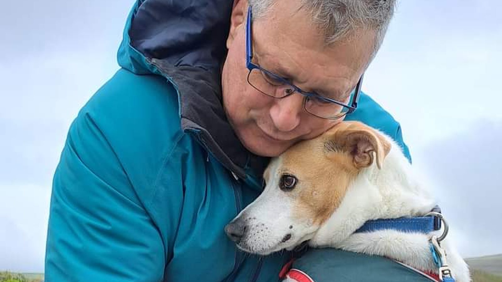 Albert holding one of his Jack Russells close on a grey day by the coast
