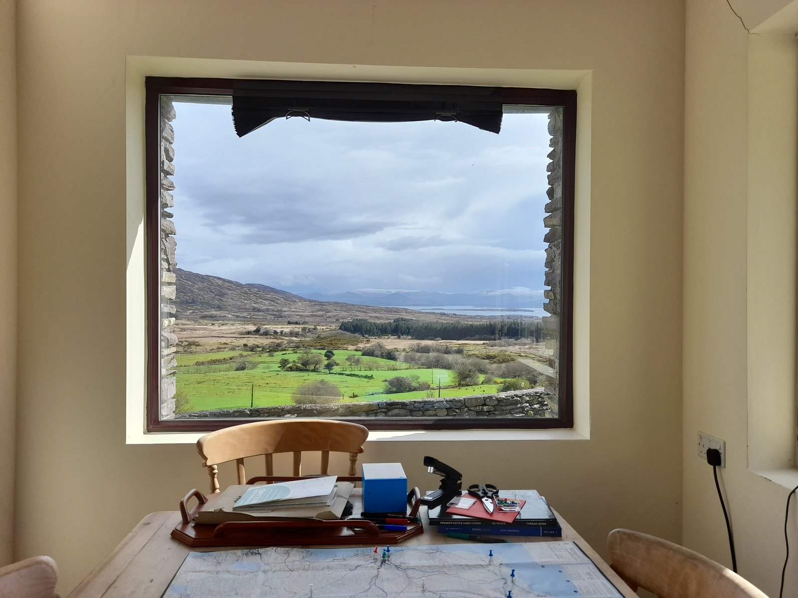 Albert's study: a map marked with pins, notebooks and pens on the table beneath a window looking over the Kerry valley
